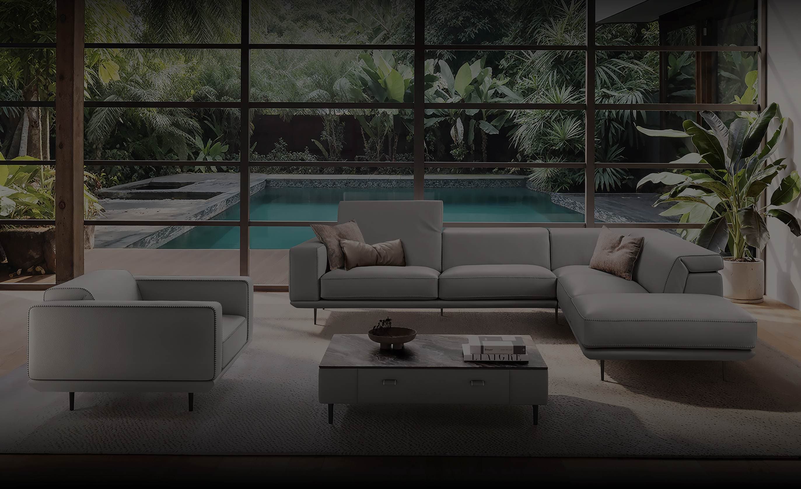 Gamma luxury living room with grey sectional sofa, armchair and coffee table overlooking tropical pool area
